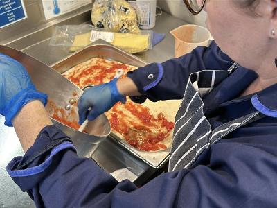 A member of catering staff preparing a fresh meal in a school kitchen
