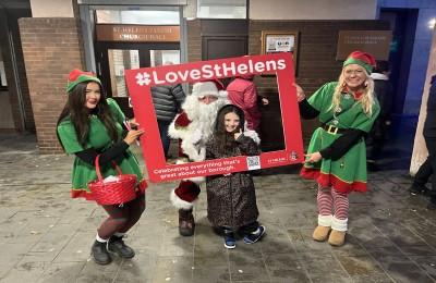Elves and Father Christmas hold up a Love St Helens picture frame outside St Helens Parish Church Hall