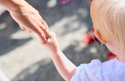 A toddler and adult hold hands